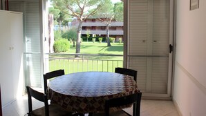 Un balcone con tavolo e sedie, vista su un edificio e una porta.
