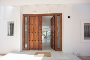 A modern interior with a wooden door, a small rug, and a window with bars.