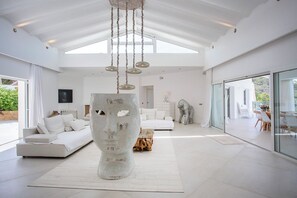 A spacious living room with a high ceiling, a large white sculpture, and a modern sofa.