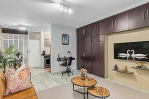 Ein modernes Wohnzimmer mit einer Couch, einem Couchtisch, einem Fernseher und dunklen Holzschränken.