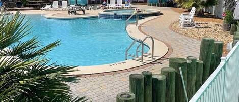 A swimming pool with a wooden deck, lounge chairs, and a building in the background.