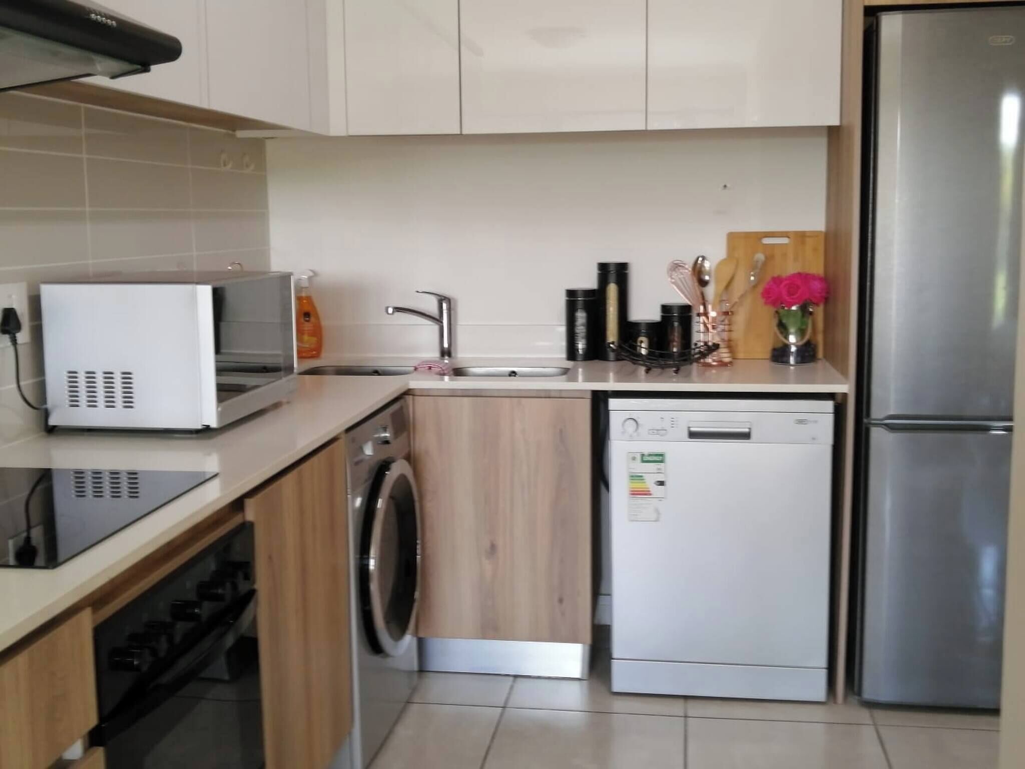 A modern kitchen with a microwave, washing machine, dishwasher, and refrigerator.