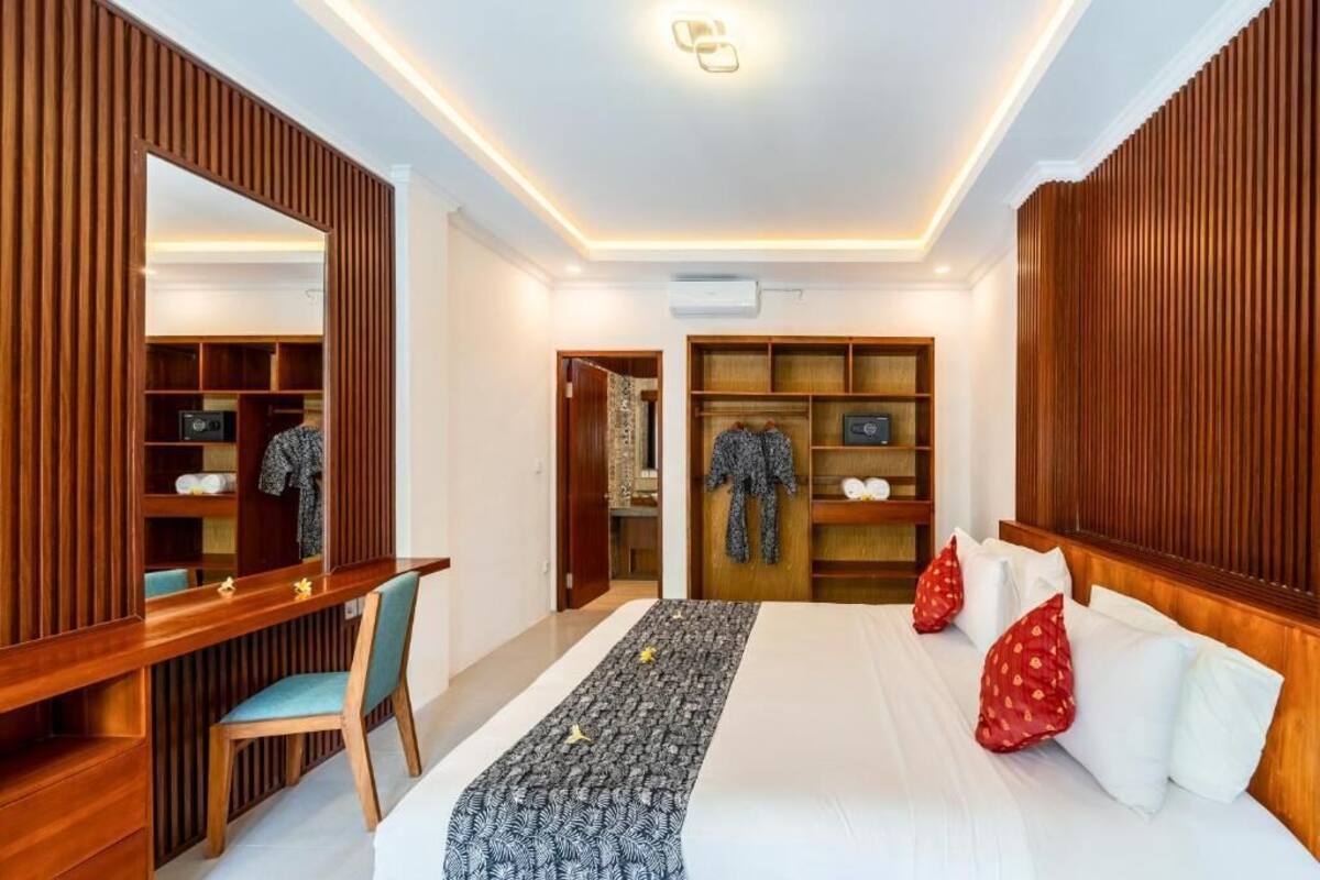 A hotel room with a bed, a desk, a chair, a wardrobe, and a mirror.