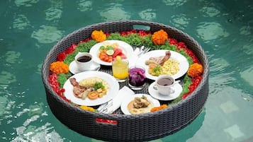 Un montaje flotante para comer con varios platos y bebidas, rodeado de flores.