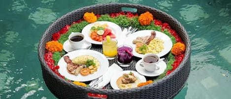 A floating dining setup with various dishes and drinks, surrounded by flowers.