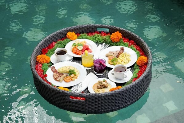 Un montaje flotante para comer con varios platos y bebidas, rodeado de flores.