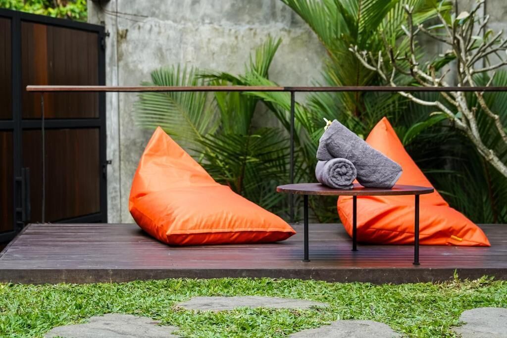An outdoor seating area with orange cushions, a small round table, and a towel.