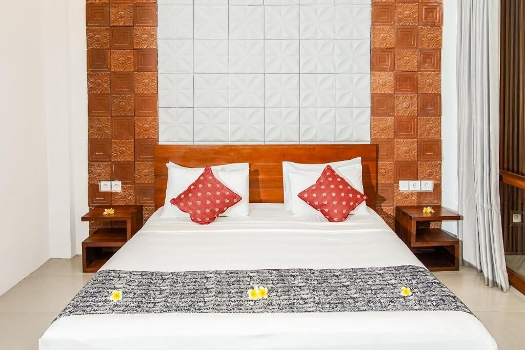 A hotel room with a large bed, wooden headboard, two nightstands, and a patterned bedspread.
