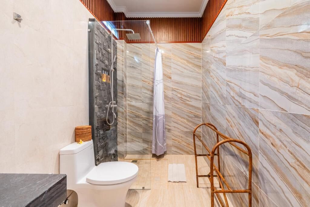 Ein Badezimmer mit Dusche, Toilette und Waschtisch mit Spiegel.