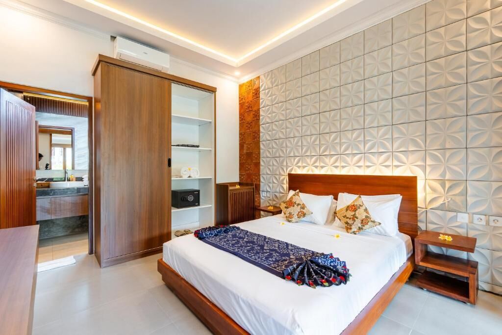 A hotel room with a large bed, a wardrobe, a vanity, and a patterned wall.