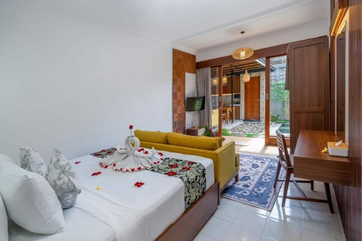 A bedroom with a bed, a sofa, a TV, and a dining area with a table and chairs.