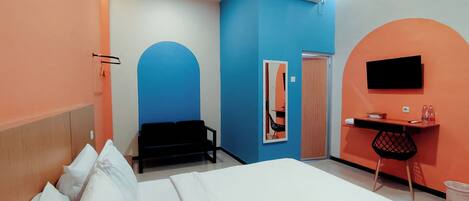 A hotel room with a bed, a desk, a chair, an air conditioning unit, and a television.