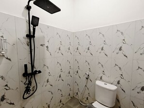 A bathroom with a shower, toilet, and marble-patterned walls. - Tripletree Kenaro Hotel (Malang)