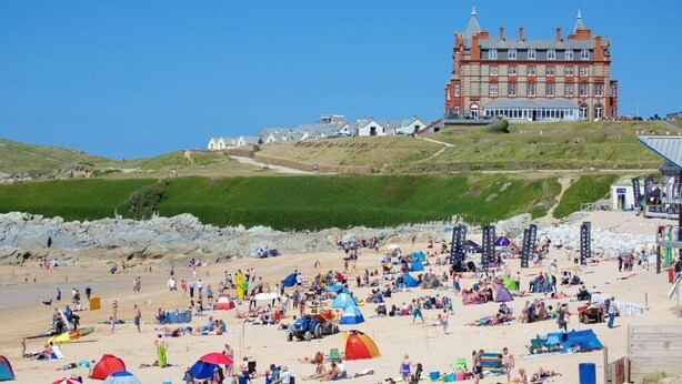 A coastal hotel with a prominent building, beach access, and tents on the sand. - Stratos Realty (Newquay)