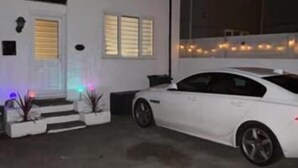 A white two-story house with a car parked in the driveway. - Stratos Realty (Newquay)