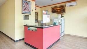 A reception desk with a red counter, a clock, and framed artwork on the walls. - Luxury Deluxe DBL Retreat W/ Free Wifi and Parking (Batam)