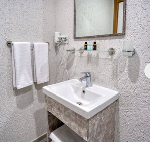 A bathroom with a white sink, two towels, a mirror, and toiletries on a shelf. - Taksim Square - Deluxe Studio 201 (Beyoğlu)