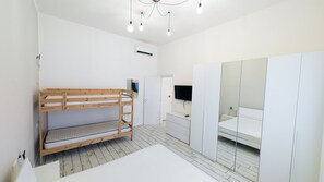 Una camera da letto con un letto a castello, un armadio, una televisione e una lampada a sospensione.