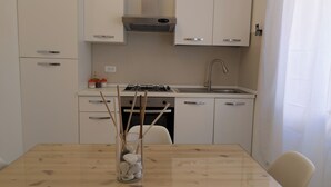 Uma cozinha moderna com armários brancos, pia de aço inoxidável e fogão a gás.