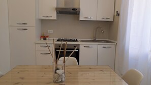 Una cucina moderna con mobili bianchi, un lavello in acciaio inossidabile e un piano cottura a gas.