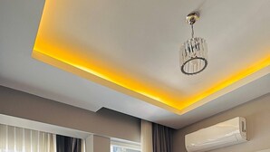 Uma sala de estar moderna com um sofá, uma TV de tela plana e um lustre.