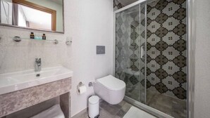Une salle de bain avec une douche à parois de verre, des toilettes blanches et un lavabo en marbre.