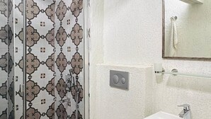 Ein Badezimmer mit Dusche, Toilette, Waschbecken und einem Mülleimer.