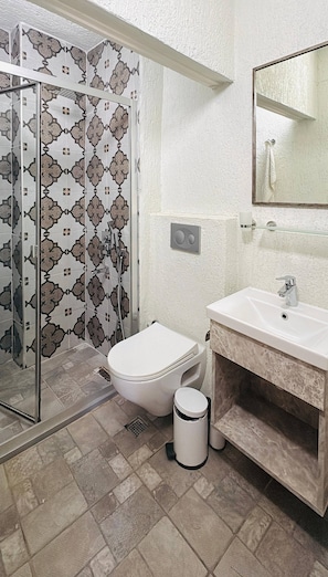 Ein Badezimmer mit Dusche, Toilette, Waschbecken und einem Mülleimer.