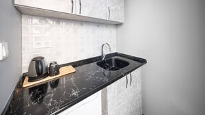 Cozinha com bancada de mármore preto, pia e cafeteira.