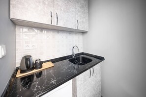 A kitchen with a black marble countertop, a sink, and a coffee maker. - Taksim Square - Deluxe Studio 302 (Beyoğlu)