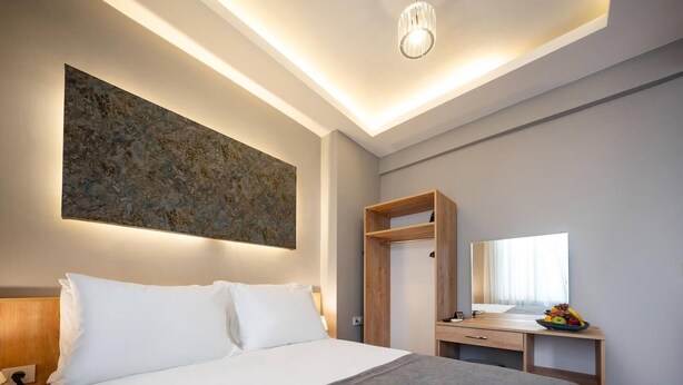 Quarto de hotel moderno com uma cama grande, uma escrivaninha de madeira com espelho e uma obra de arte na parede.
