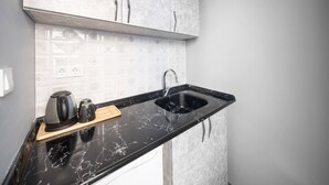 A kitchen with a black marble countertop, a sink, a kettle, and a coffee maker. - Taksim Square - Deluxe Studio 202 (Beyoğlu)