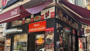 A street food stall with a Coca-Cola sign, food menu, and people dining outside. - Taksim Square - Deluxe Studio 202 (Beyoğlu)