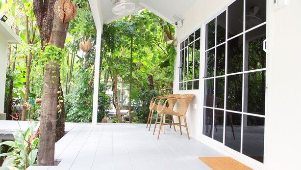 A covered outdoor area with white flooring, a large window, and a white door. - Homeku Guesthouse Room 3 Cozy Stay Close to Suvarnabhumi Airport (Lat Krabang)