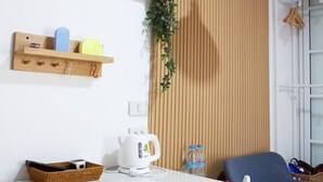 A dining area with a white table, chairs, a hanging light fixture, and wooden shelves with various items. - Homeku Guesthouse Room 3 Cozy Stay Close to Suvarnabhumi Airport (Lat Krabang)