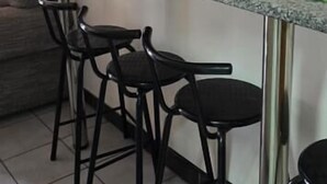 A kitchen area with a counter, two black chairs, a mirror, and a framed picture on the wall. - Summer sands Air b n b (Durban)