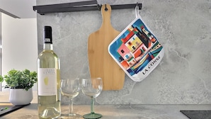 Una bottiglia di vino Terra Corsa, due bicchieri da vino e un tagliere colorato con la scritta 'LA CORSE'.