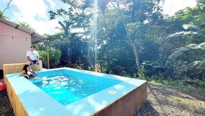 A rectangular swimming pool with a wooden deck, surrounded by dense greenery and trees. - Romantic Suite with Pool (chachagua)