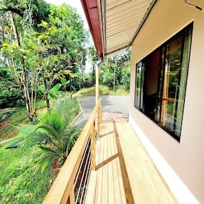 A wooden deck with a view of a garden and a building. - Romantic Suite with Pool (chachagua)