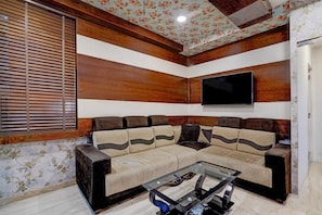 A living room with a sectional sofa, a flat-screen TV, and a glass coffee table. - Townhouse Oak Science Gallery Bengaluru (Bengaluru)