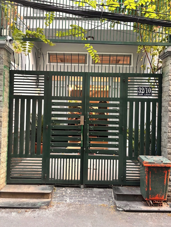 Una entrada con puerta metálica y un letrero que dice '32/10 ME LINH'.