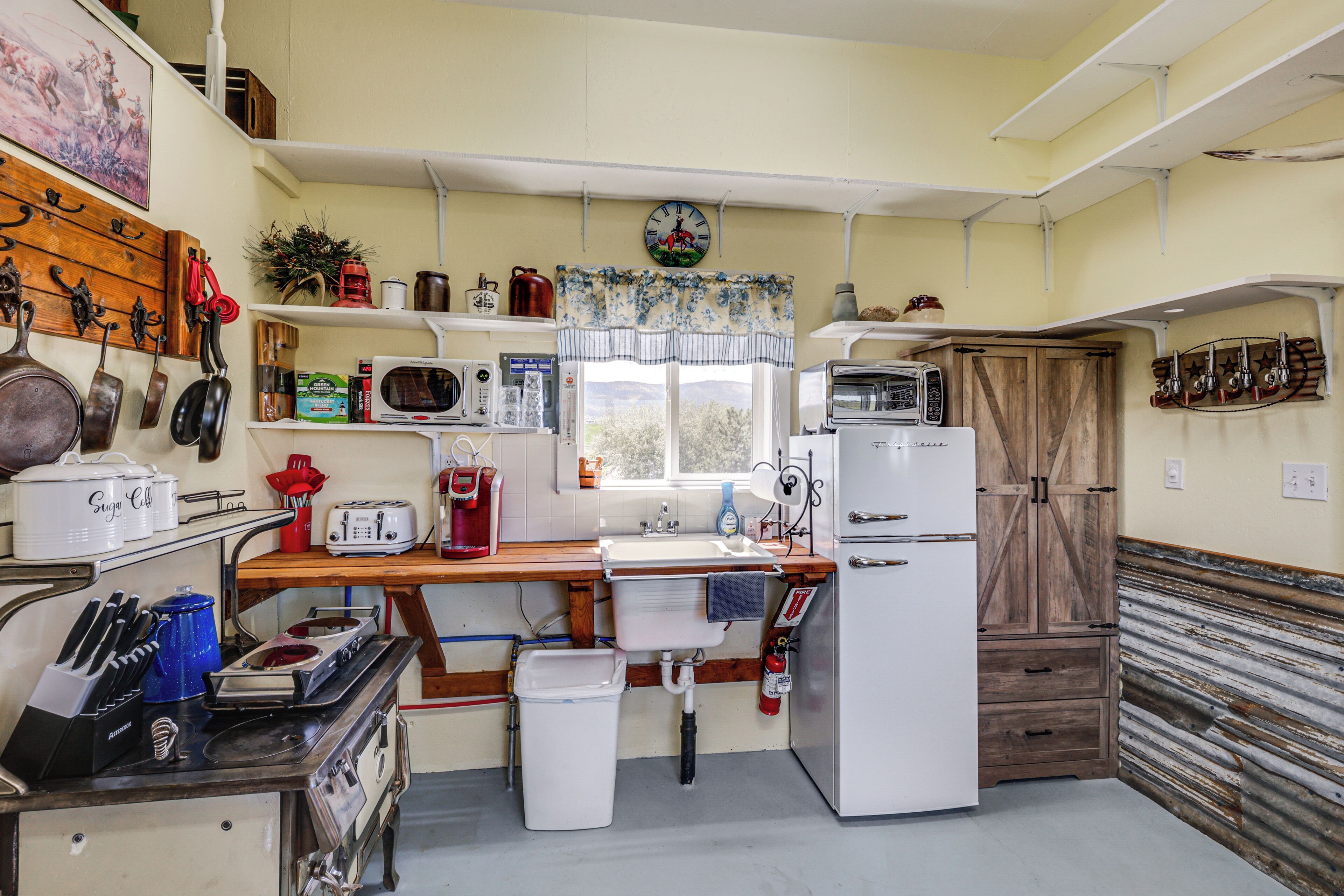 Een keuken met een houten aanrecht, een spoelbak, een koelkast, een magnetron en diverse keukengerei.