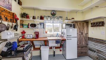 Een keuken met een houten aanrecht, een spoelbak, een koelkast, een magnetron en diverse keukengerei.