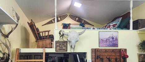Ein Zimmer mit Hochlakenbett, einem aufgehängten Schädel, an der Wand befestigten Kochutensilien und einem Schild mit der Bitte, Sporne abzulegen.
