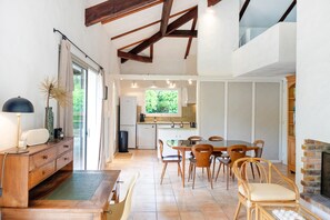 A spacious kitchen with a dining area, wooden furniture, and a fireplace. - Holiday Home in Hossegor with Garden under the Pines and Covered Terrace (Hossegor)