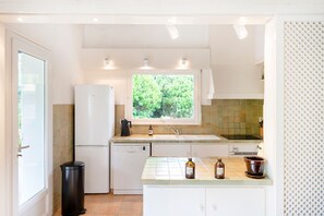 A compact kitchen with a window, white cabinets, and a tiled backsplash. - Holiday Home in Hossegor with Garden under the Pines and Covered Terrace (Hossegor)