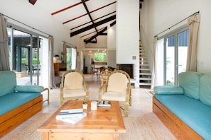 Amplia sala de estar con sofá, sillones, una mesa de centro y una cocina al fondo.