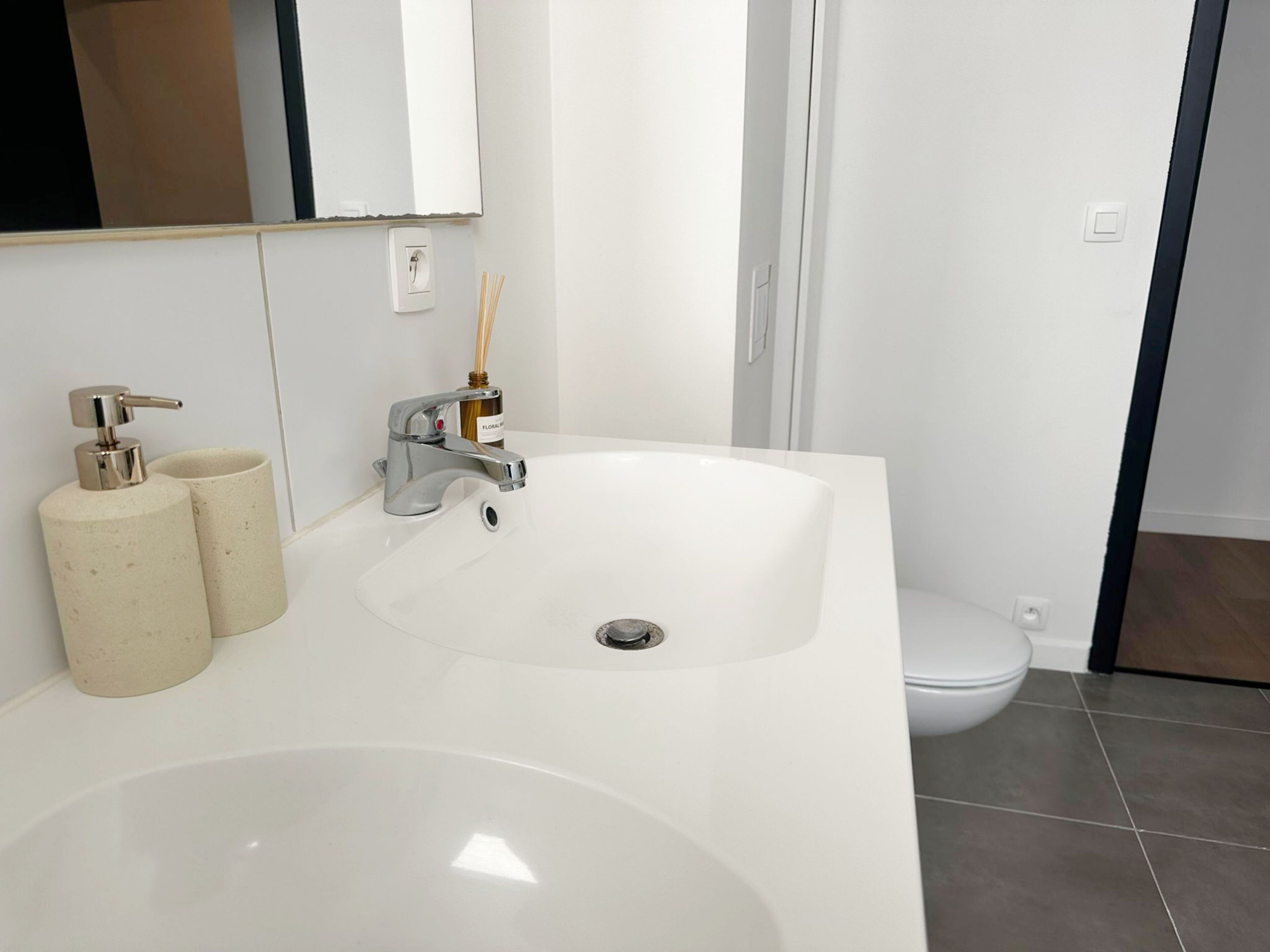 Un baño con lavamanos blanco, un espejo, un inodoro y una zona de ducha.