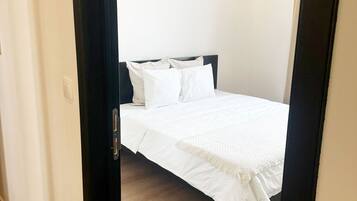 Ein Schlafzimmer mit einem Bett, weißer Bettwäsche, einem dunklen Kopfteil und Holzboden.