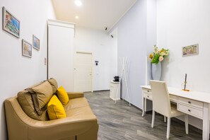 A modern hotel room with a leather sofa, a desk, a chair, and a coffee machine. - Agorà Borsa (Naples)